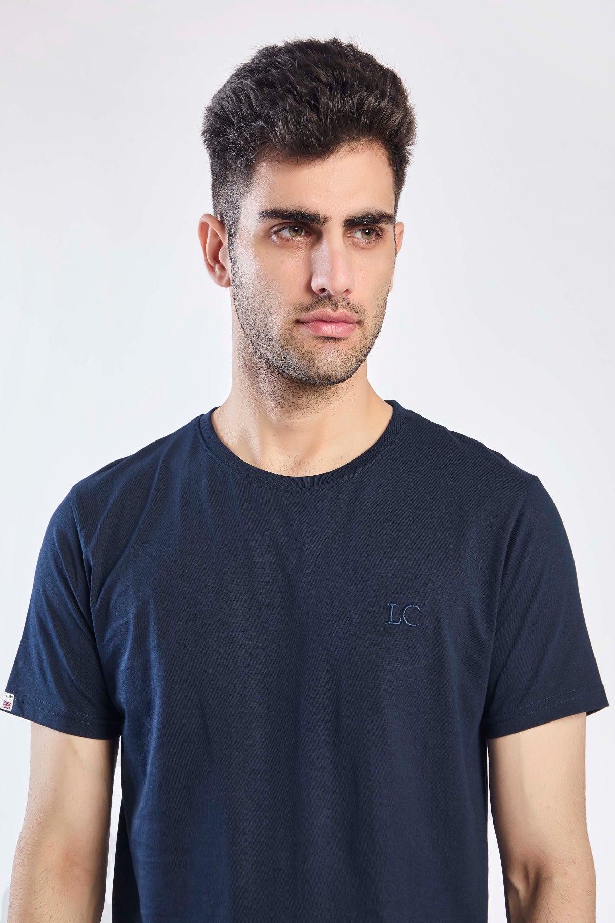 Man wearing a navy blue t-shirt with a logo on a white background