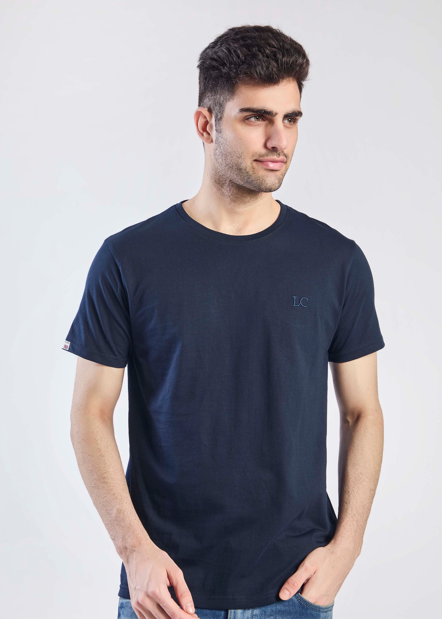 Man wearing a navy blue t-shirt with a logo on a white background front pose